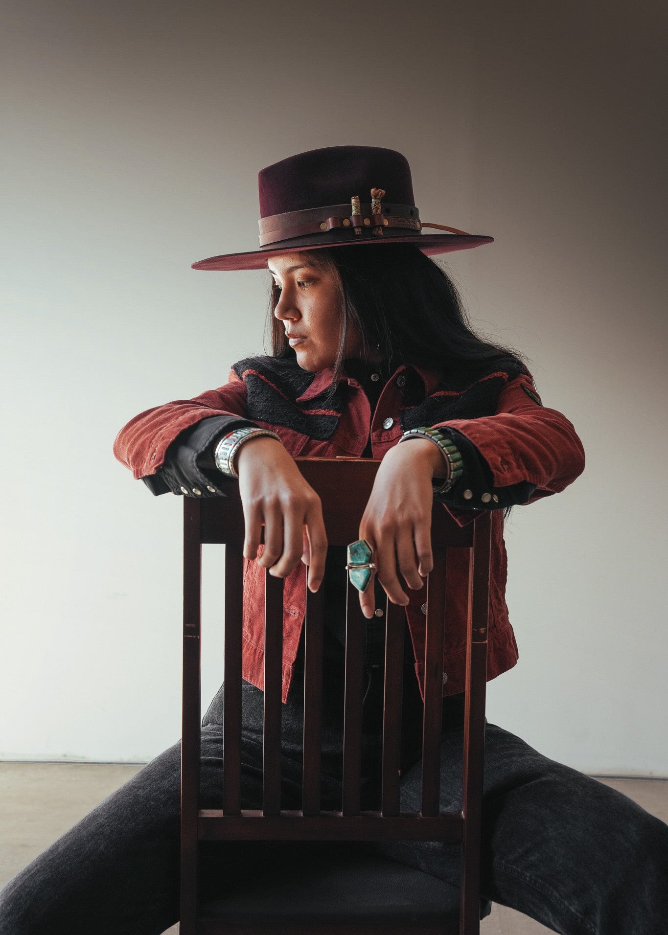 Person wearing a red jacket and hat, sitting on a chair against a plain background